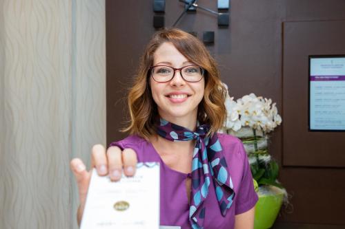 a woman is holding up a piece of paper at Mercure Lyon Est Chaponnay in Chaponnay