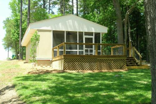 a small house with a porch in the grass at Captain's Cove in Lake Murray Shores