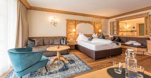 a hotel room with a bed and a couch at Quellenhof Luxury Resort Passeier in San Martino