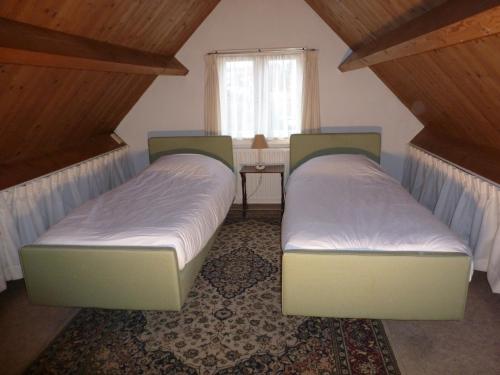 dwa łóżka w małym pokoju z oknem w obiekcie Huis De Roos w mieście De Kwakel