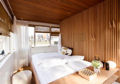 een slaapkamer met een wit bed en een houten muur bij SWEETS - Buiksloterdraaibrug in Amsterdam