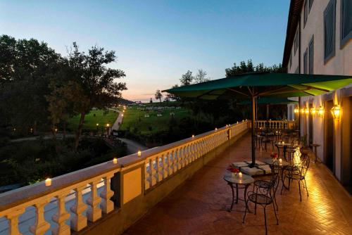 a balcony with tables and chairs and an umbrella at Hotel Terme di Stigliano in Canale Monterano