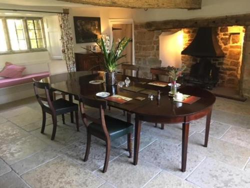 a dining room with a table and chairs and a fireplace at Hollow Meadow House in Priors Marston