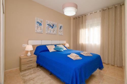 ein Schlafzimmer mit einem blauen Bett und einem Fenster in der Unterkunft San Julían Apartamento in Torrevieja