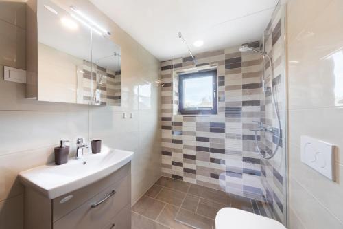 een witte badkamer met een wastafel en een douche bij Lake Bled Apartment Marjetka in Bled