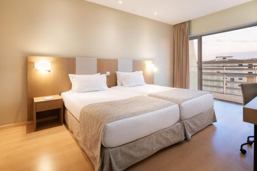 
a hotel room with a bed and a desk at Eurostars Oasis Plaza in Figueira da Foz
