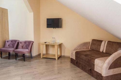 a room with a couch and two chairs and a tv at Hostynnyy Dvir in Stryi