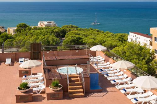a balcony with a pool and chairs and umbrellas at htop Molinos Park - Fun in Salou