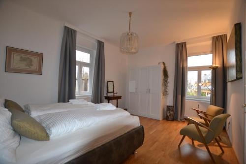 a bedroom with a bed and a chair and windows at Apartment Graz-Ulrichsbrunn, free parking in Graz