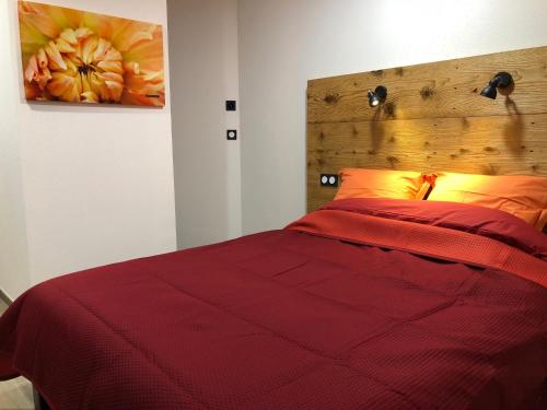 a bedroom with a red bed with a wooden headboard at La Datcha du Parc in Husseren-Wesserling