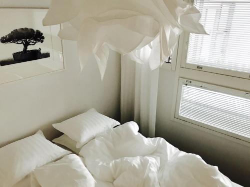 a bed with white sheets and pillows next to a window at Helsinki 00100 Vuorikatu 40,5 m2 in Helsinki