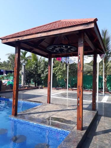 a wooden pavilion next to a swimming pool at Sea Land Kihim in Alibaug