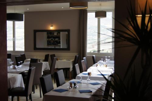 a dining room with white tables and chairs and windows at La Clavelière in Saint-Auban-sur-Ouvèze