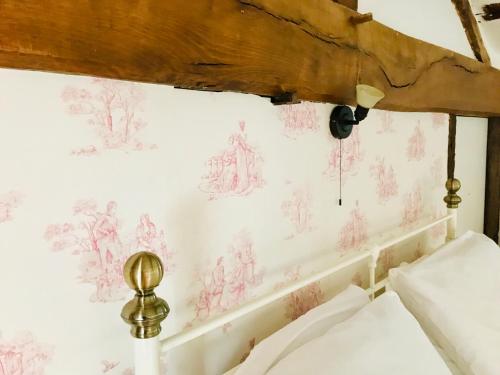 a bedroom with pink drawings on the wall at La Blatière French Cottages in La Chapelle-Saint-Étienne