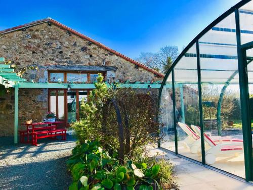 a glass greenhouse in front of a stone house at La Blatière French Cottages in La Chapelle-Saint-Étienne