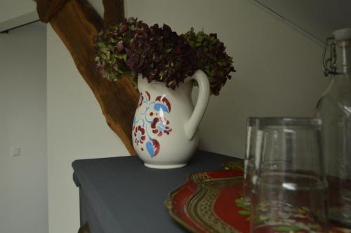 a white vase with a plant in it on a table at B&B de Pottenbakkershoeve in Meerlo