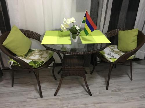 ein Tisch mit Stühlen und einer Vase mit Blumen darauf in der Unterkunft The Octagon wing A in Beau Vallon