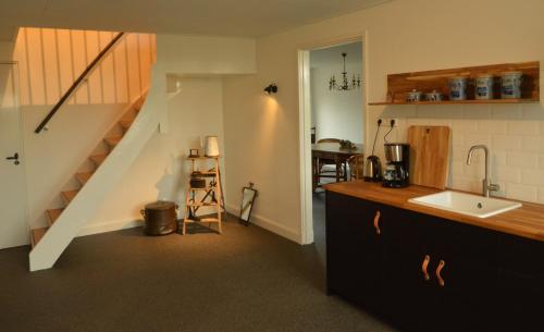 a kitchen with a staircase with a sink and a counter at B&B de Pottenbakkershoeve in Meerlo