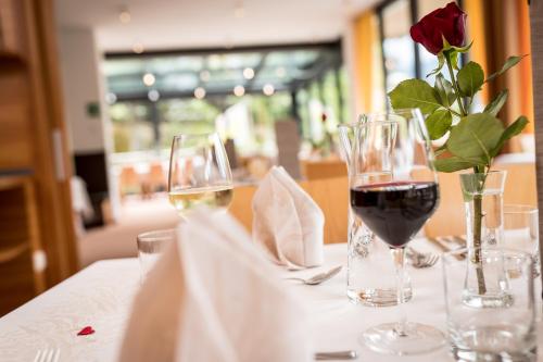 uma mesa com dois copos de vinho e uma rosa em Mounthotel Niggl em Nova Levante