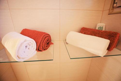 - deux serviettes sur une étagère en verre dans une salle de bains dans l'établissement HMM Apartament, à Sibiu