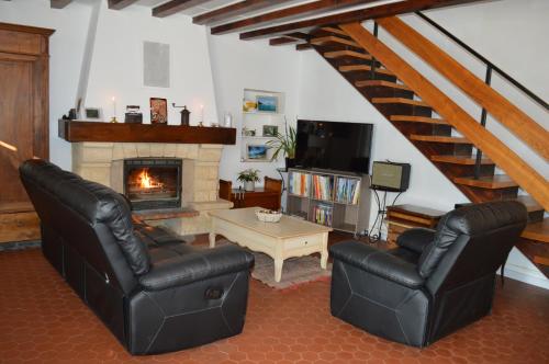 a living room with two leather chairs and a fireplace at le domaine du chaffard in Les Avenières