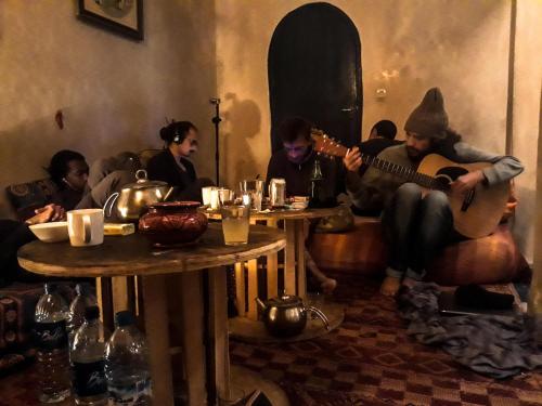 a group of people sitting in a living room playing guitar at The Chill Art Hostel in Essaouira