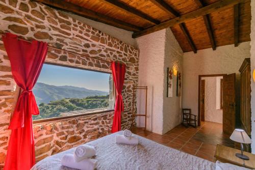 a bedroom with a large window in a stone wall at Complejo Rural El Mirador in Málaga