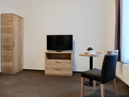 a room with a tv and a table with a chair at Penzion Stará pošta in Frýdek-Místek