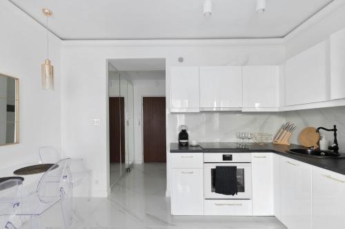 Biała kuchnia z białymi szafkami i kuchenką w obiekcie Grand Theatre Prime Apartment w Warszawie