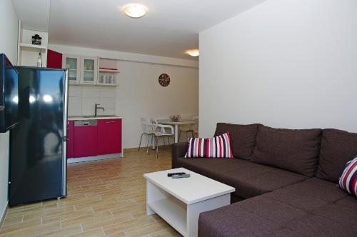 a living room with a brown couch and a kitchen at Apartments Lena in Bol