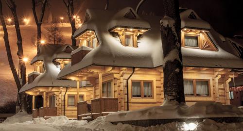 una casa cubierta de nieve por la noche con luces en Osada Harenda, en Zakopane