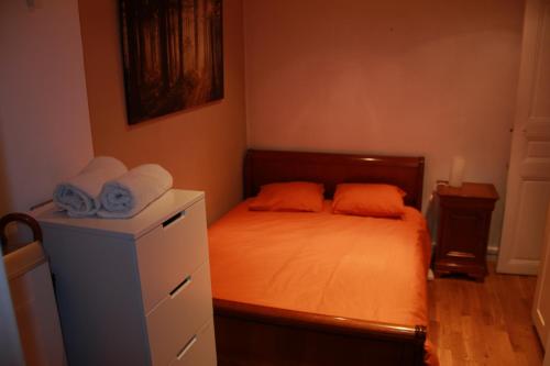 una piccola camera da letto con un letto con lenzuola arancioni e asciugamani di SmartApart, Heart of Paris, Top Quality 10 a Parigi