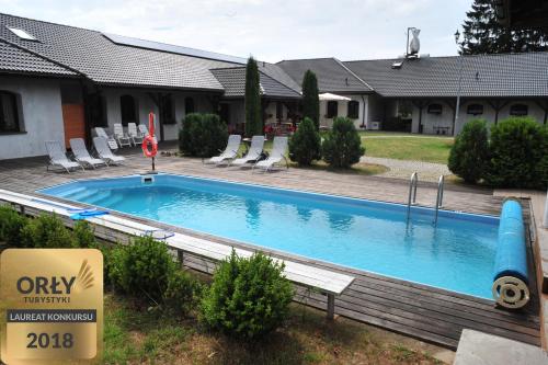 una piscina en un patio con sillas y una casa en Ranczo Sielanka en Jamielnik