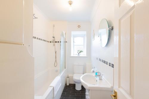 a white bathroom with a sink and a toilet at Spacious 2BR Flat in Stansted in Stansted Mountfitchet