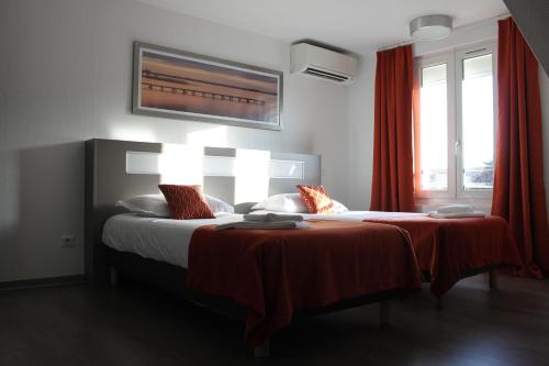 a bedroom with two beds with red curtains at Hôtel du Centre in Soustons