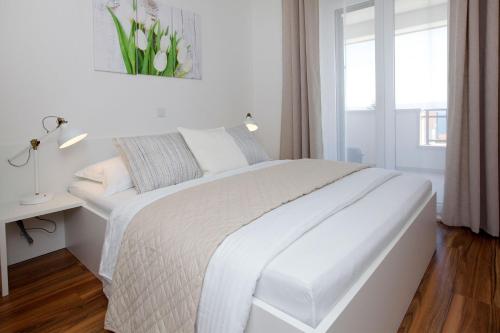 a white bedroom with a white bed and a window at Apartments Lena in Bol