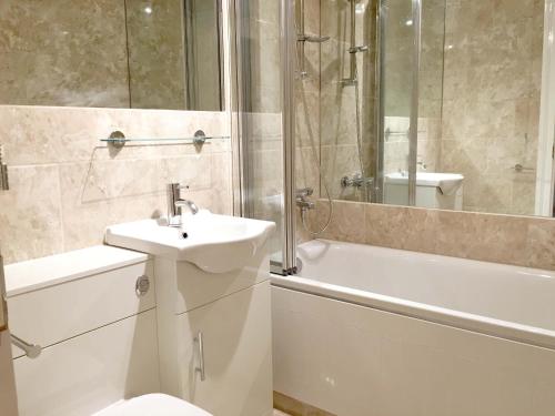 ein Badezimmer mit einem Waschbecken, einem WC und einer Badewanne in der Unterkunft Elegant Fitzrovia 2-bed w Wifi: Close to Oxford Street W1 in London