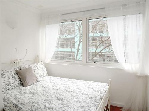 ein weißes Schlafzimmer mit einem Bett und einem Fenster in der Unterkunft Elegant Fitzrovia 2-bed w Wifi: Close to Oxford Street W1 in London