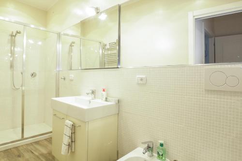 een witte badkamer met een wastafel en een douche bij Charming and cosy apartment in Bologna