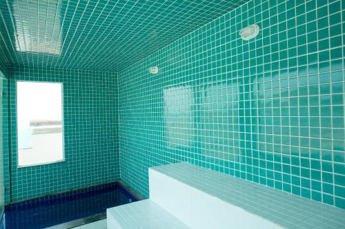 baño de azulejos verdes con bañera y ventana en AP ESPETACULAR VISTA MAR PRAINHA EM ARRAIAL DO CABO, en Arraial do Cabo