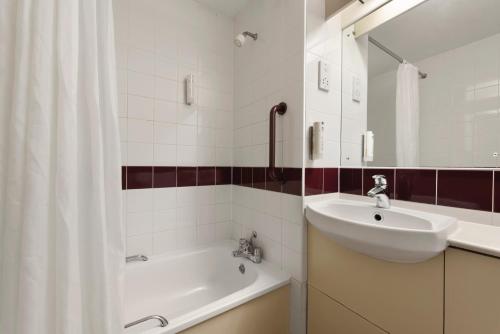 a bathroom with a sink and a tub and a mirror at Days Inn Hotel Gretna Green in Gretna Green
