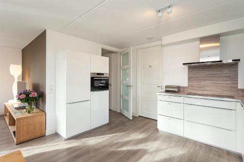 a kitchen with white cabinets and a wooden table at Buitenplaats Witte Raaf aan Zee in Noordwijk