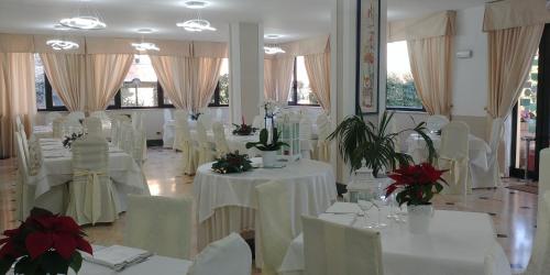 a room filled with white tables and chairs with flowers at Hotel Caserta Antica in Caserta