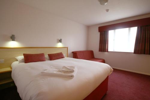 a hotel room with a large white bed and a chair at Days Inn Hotel Gretna Green in Gretna Green