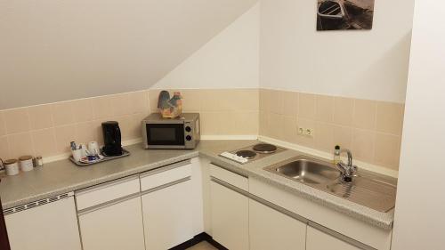 a small kitchen with a sink and a microwave at Stadthotel am Bühnenhaus in Kevelaer