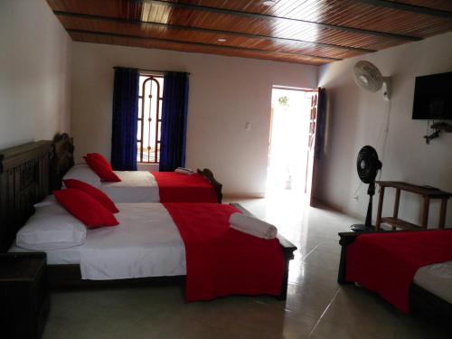 a bedroom with two beds with red and white sheets at Hotel campestre la Maria in Villavicencio