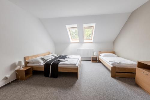 a bedroom with two beds and two windows at Pivovar a Penzion GRASEL in Český Rudolec
