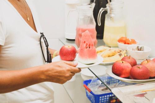 a person holding a plate of apples and a drink at Pousada Águas Marinhas in Maceió