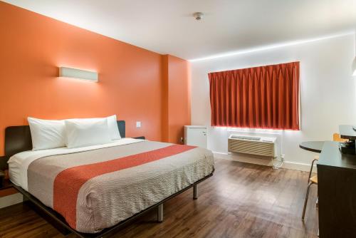 a bedroom with a bed with orange walls and a window at Motel 6-Moncton, NB in Moncton