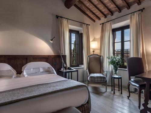 a bedroom with a bed and a desk and a chair at Castel Monastero - The Leading Hotels of the World in Castelnuovo Berardenga